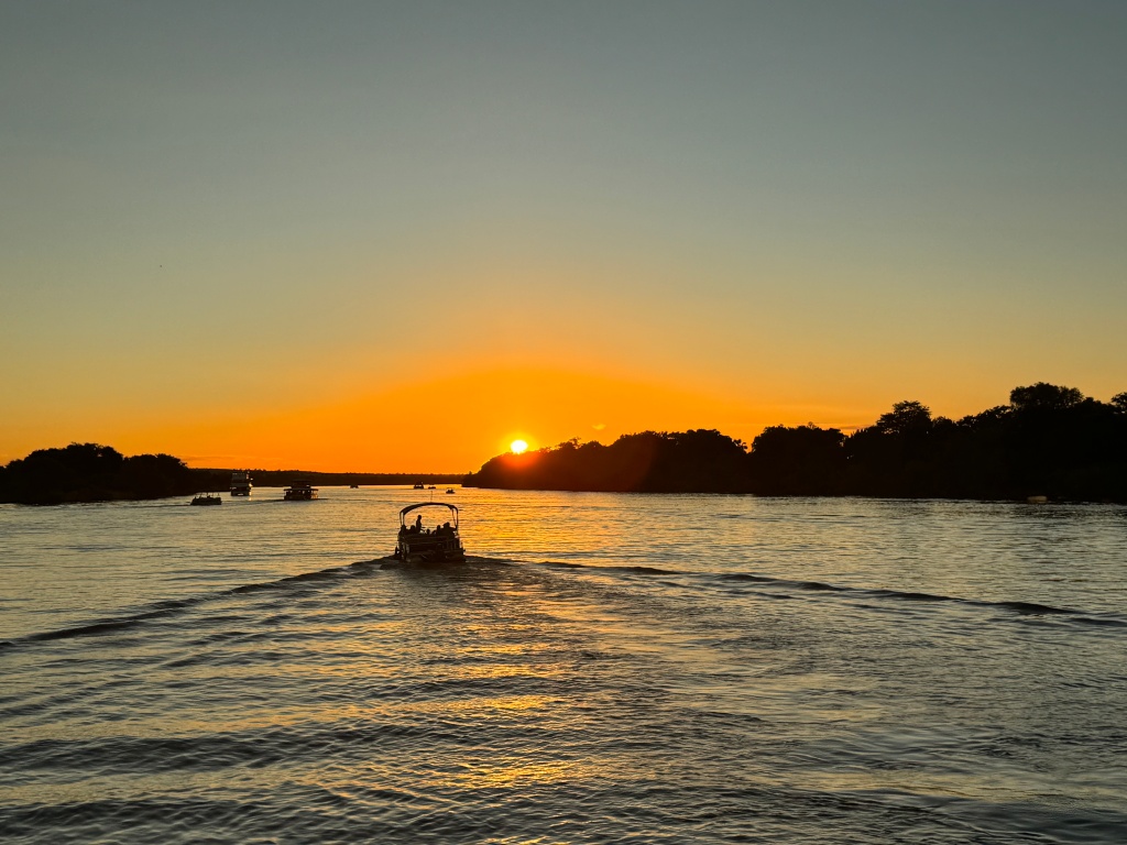 Boats on the Zambezi river as the sun sets
